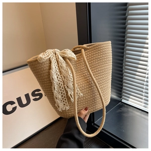 Chic beige woven shoulder bag featuring a large white lace bow for a trendy summer look