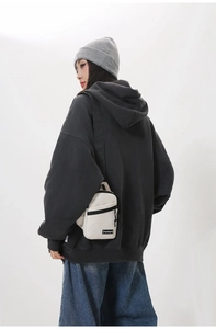 Detail of off-white nylon crossbody bag with black zipper and branded woven label