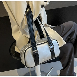 Detail of silver boston bag in metallic PU leather worn by a model in a beige blazer