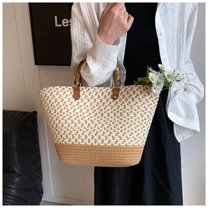Detail of hand-woven straw tote with bamboo handles and chic bicolor contrast stitching