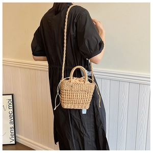 Minimalist straw bucket bag with mesh texture and drawstring liner on model back