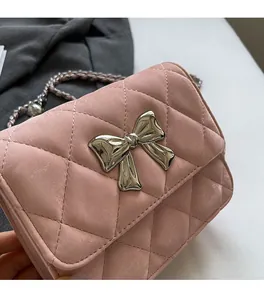 Close-up of pink quilted PU leather bag with silver bow buckle and woven chain strap