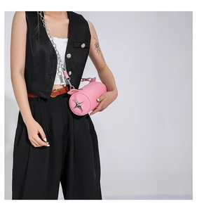 Detail view of pink cylinder bag with silver star emblem and chunky metal chain