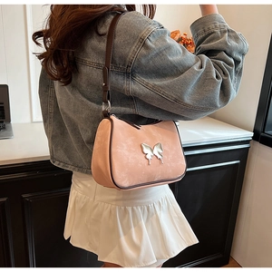 Détail du sac à bandoulière en similicuir rose avec ornement papillon argenté