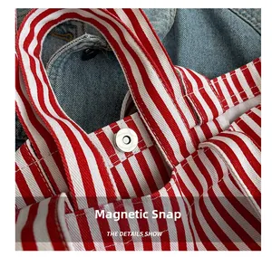 Detail view of the silver magnetic snap closure on a red and white striped canvas tote bag