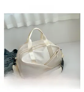 Detail view of cream waterproof nylon travel bag with detachable shoulder strap and metal hardware