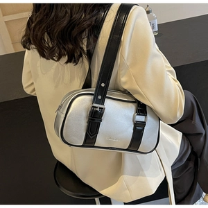 Close-up of a silver metallic shoulder bag featuring black leather straps and brand logo