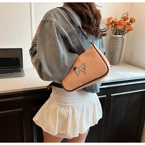 Détail du sac bandoulière rose en demi-lune avec boucle papillon argentée élégante