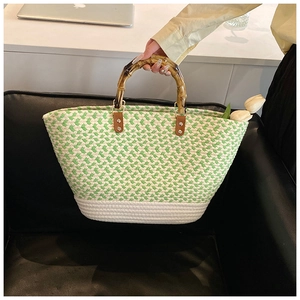 Close-up of green and white woven handbag with natural bamboo handle and tulip decoration