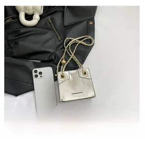 Macro detail of silver mirror finish PU leather shoulder bag with metal chain and grommets