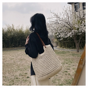 Detail of hand-woven tote bag with beige mesh pattern and brown leather straps