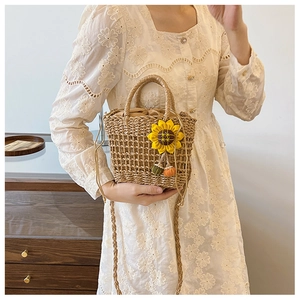 Detail of hand-woven straw bag with sunflower charm and drawstring inner lining