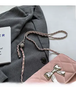 Close-up of pink quilted faux leather shoulder bag with a large silver metal bow detail