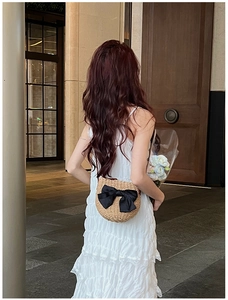 Détail du sac bandoulière en paille beige avec un grand nœud en satin noir au dos