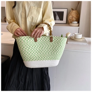 Detail of woven tote bag with bamboo handles and green wavy pattern in summer style