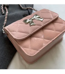 Detail of pink quilted PU leather crossbody bag with silver bow clasp and chain strap