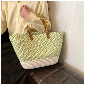 Detail of woven tote bag featuring striped green fabric and natural bamboo handles