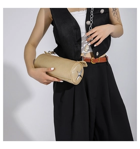 Detail view of champagne gold barrel bag with star emblem and metal chain strap