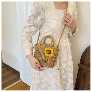 Close-up of woven straw handbag featuring a decorative sunflower and drawstring closure
