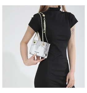 Close-up of a mini silver mirror crossbody bag with a golden chain strap and logo detail