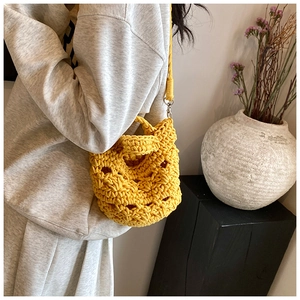 Detail view of bright yellow hand-woven knit bag with silver metal strap hooks
