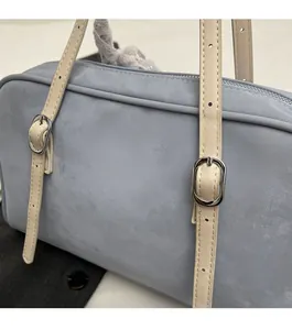 Close-up of adjustable silver buckle and light beige leather strap on a blue handbag