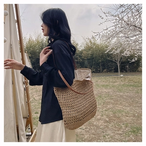 Detail view of woven straw tote bag with brown leather handles and inner fabric lining