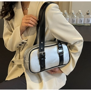 Chic silver metallic shoulder bag with black strap and buckle detail shown on a model