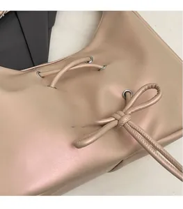 Detail of light beige faux leather handbag featuring pearl finish and drawstring bow