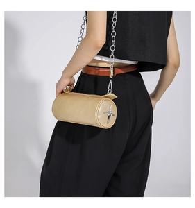 Detailed view of golden cylindrical PU leather bag with silver star and metal chain
