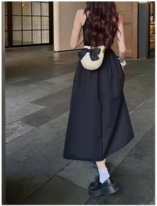 Détail d'un sac bandoulière en paille orné d'un grand nœud en soie noire sur tissu tissé