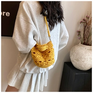 Detail of yellow hand-woven knit crossbody bag with hollow crochet texture on model