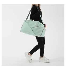 Detail of mint green nylon sports bag worn by model showing side profile and large capacity
