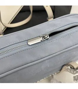 Close-up of smooth silver metal zipper and soft light blue suede texture on handbag