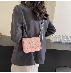 Pink quilted crossbody bag with silver bow accent shown on model for size perspective