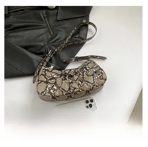 Detail of snake print leather underarm bag with silver buckle and rivet hardware accents