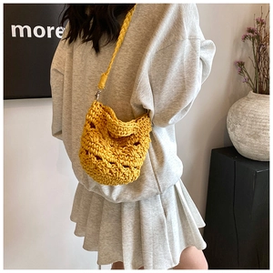 Detail view of yellow crochet knit crossbody bag with woven patterns on model shoulder