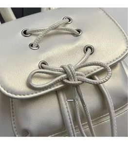 Detail of pearlescent white PU leather backpack with ribbon lacing and silver eyelets