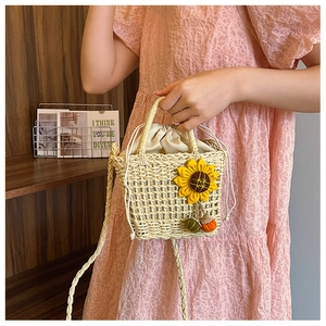 Detail of hand-woven straw bag featuring sunflower decor and acorn charms with drawstring lining