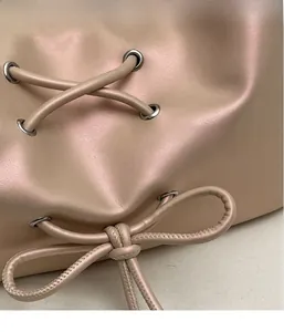 Detail view of pearlescent PU leather cross-body bag with silver eyelets and drawstring