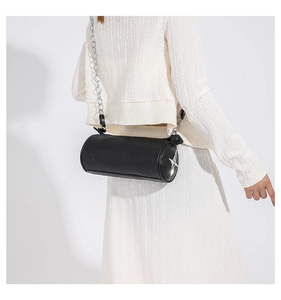 Detail of black cylinder bag with silver star ornament and metal chain strap on model