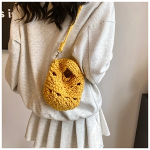 Detail of yellow hand-knitted crossbody bag showing thick crochet texture and metal buckle