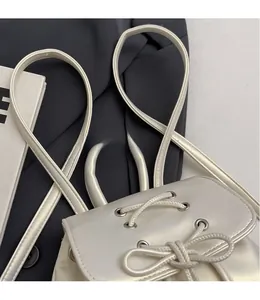 Detail of cream PU leather backpack featuring drawstring closure and slim shoulder straps