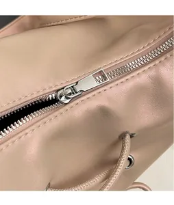 Detailed macro view of the smooth silver metal zipper on the light pink leather handbag