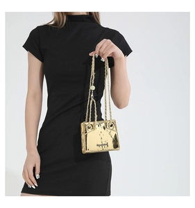 Close-up of golden metallic mini bag with chain strap on black dress outfit