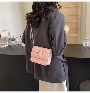 Detail of pink quilted PU leather crossbody bag with silver bow accent and chain strap