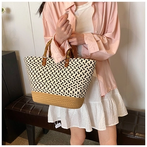 Detail of woven tote bag featuring bamboo handles and geometric black and white patterns
