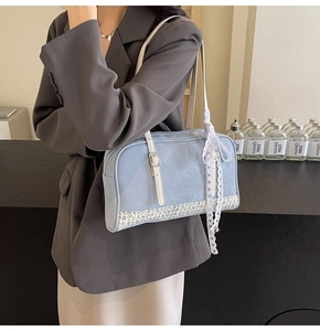 Detail of light blue faux suede handbag featuring floral bottom and white lace bow