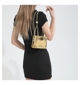 Detailed view of metallic gold mini shoulder bag with chain strap on a black dress