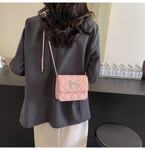Detail of pink quilted PU shoulder bag with metal bow clasp and chain strap